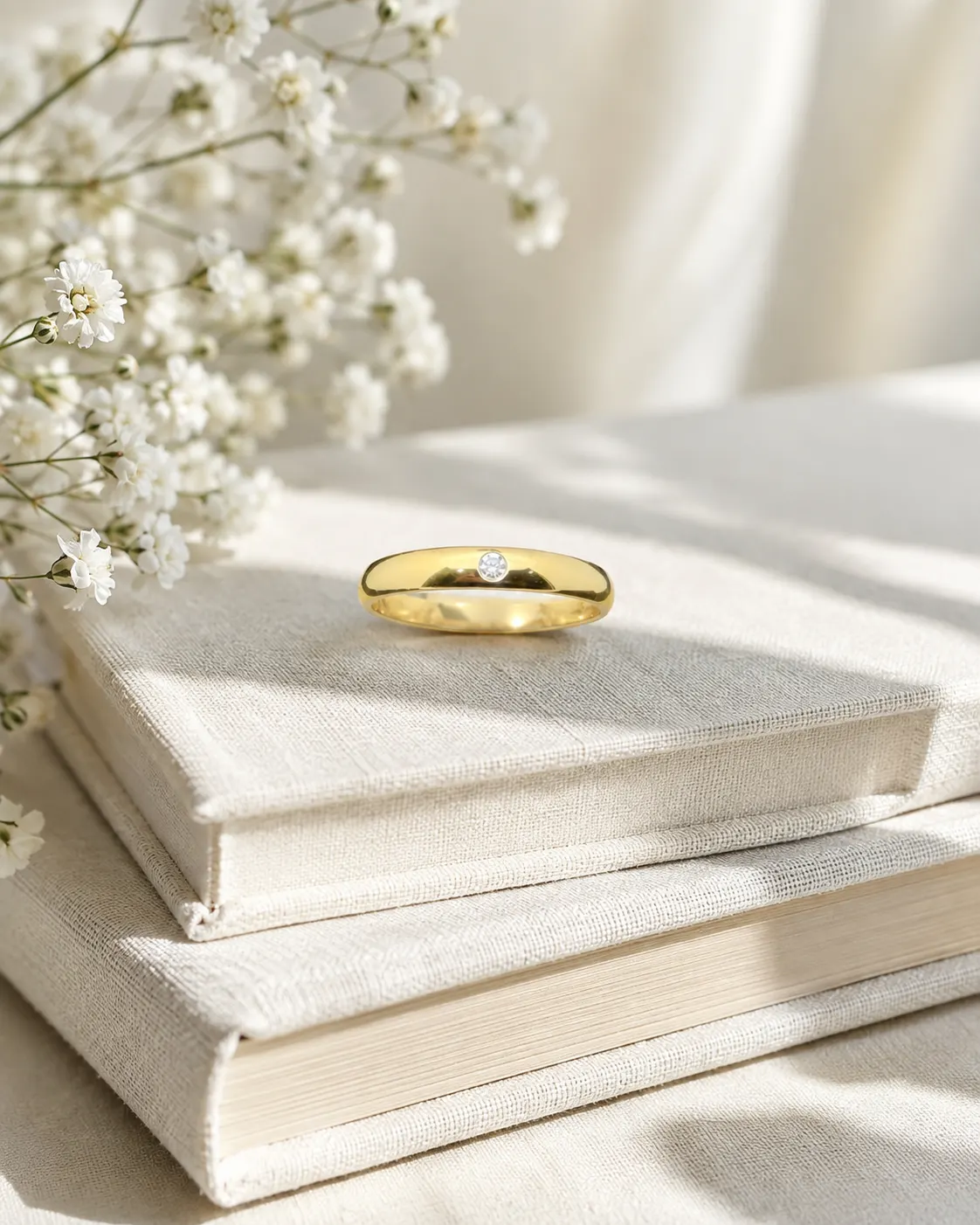 Gold solitaire band on linen-bound books with flowers